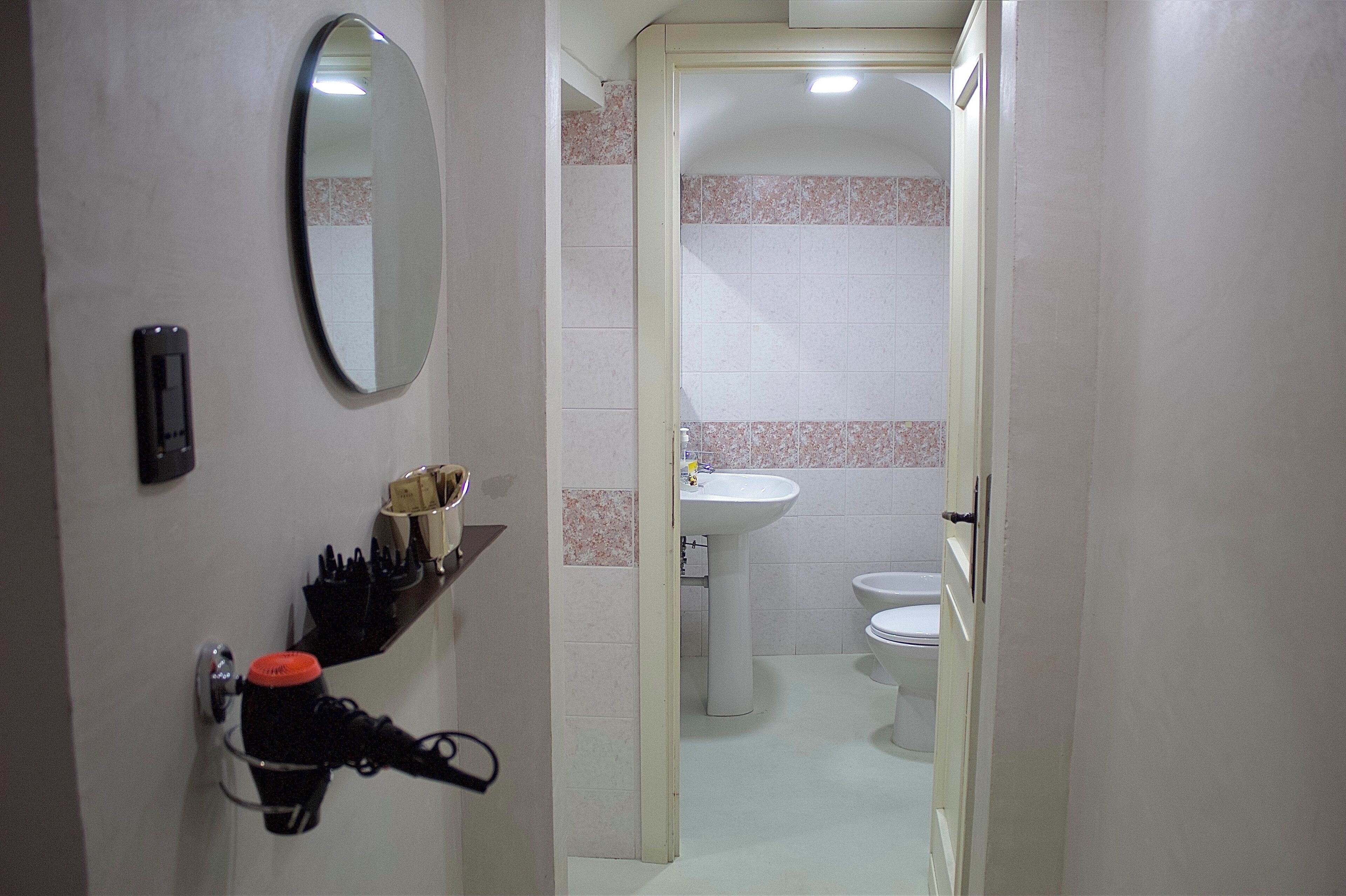 Un pasillo estrecho que conduce a un baño con lavamanos e inodoro.