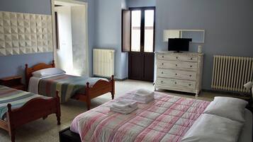 Ein Schlafzimmer mit zwei Betten, einem Schminktisch, einem Heizkörper und einem Fernseher.