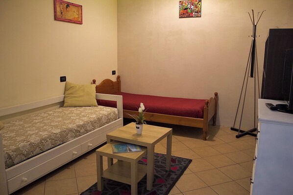 A small, well-lit room with two single beds, a small table with a plant, and a standing lamp. - Il castello di atessa  (Atessa)