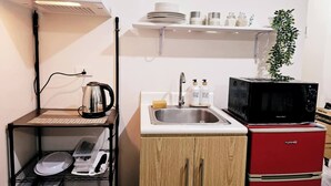 Cozinha compacta com micro-ondas, pia e armário pequeno.