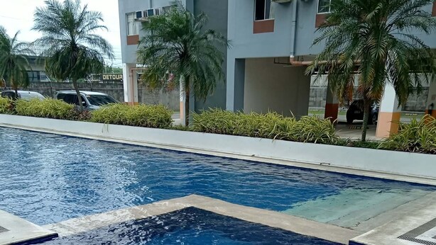 Piscina com borda azulejada, ladeada por um calçadão.