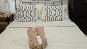 Cama bem arrumada com almofadas estampadas, uma obra de arte emoldurada na parede e um cesto de vime sobre a cama.