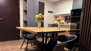 Una cocina moderna con una mesa de comedor de madera, sillas negras y dos jarrones con flores amarillas.