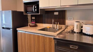 Una cocina moderna con microondas integrado, pileta de acero inoxidable y tetera sobre la encimera.