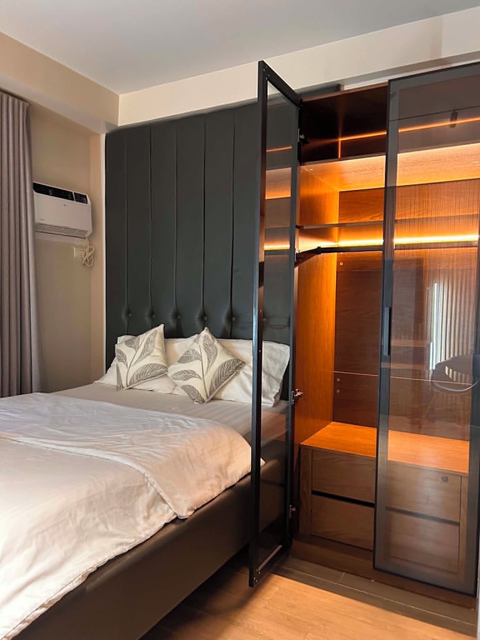 A bedroom with a bed, a wardrobe, and a built-in air conditioning unit.
