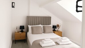 Un dormitorio moderno con una cama grande, dos mesitas de noche y un techo inclinado.