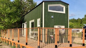 A green metal building with a wooden deck and a white-framed window. - "Fuchs und Igel Tiny House" - Time out in the newly designed "Fuchs" Tiny House (Grünheide (Mark))
