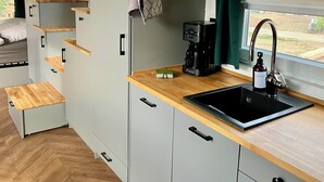 A compact kitchenette with a sink, coffee maker, and storage cabinets. - "Fuchs und Igel Tiny House" - Time out in the newly designed "Fuchs" Tiny House (Grünheide (Mark))