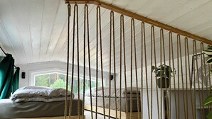 A room with a bed, a small table, and a hanging plant. - "Fuchs und Igel Tiny House" - Time out in the newly designed "Fuchs" Tiny House (Grünheide (Mark))