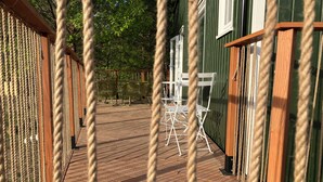 A wooden deck with rope barriers, white folding chairs, and a green building in the background. - "Fuchs und Igel Tiny House" - Time out in the newly designed "Fuchs" Tiny House (Grünheide (Mark))