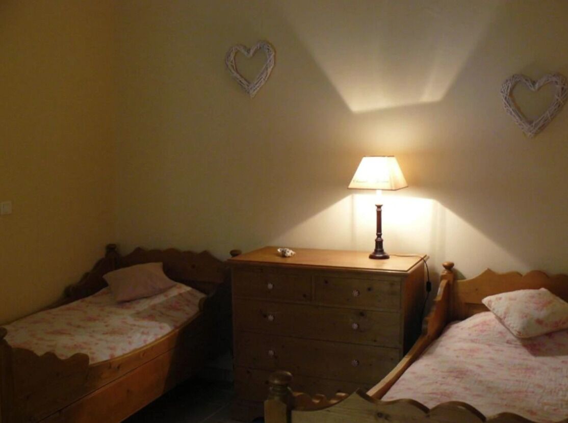 A bedroom with two single beds, a dresser, and a lamp.