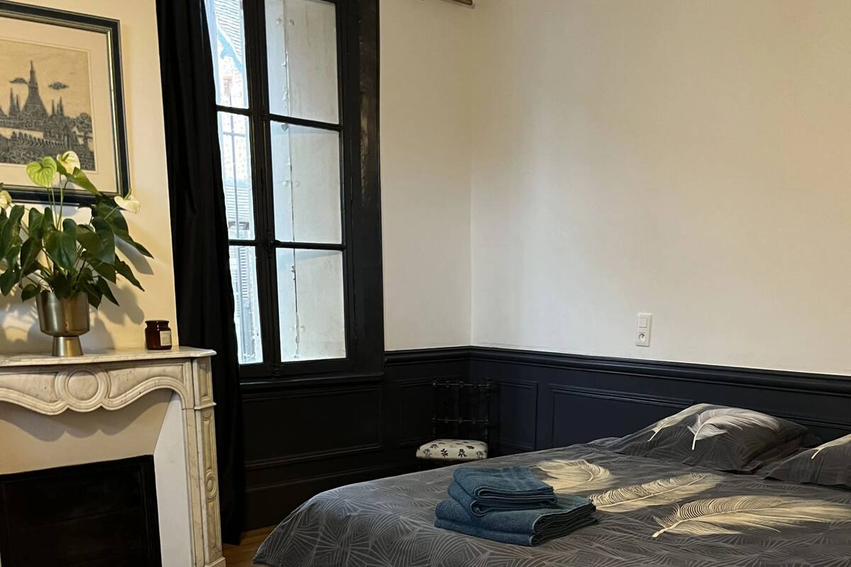 A bedroom with a bed, a fireplace, and a window.