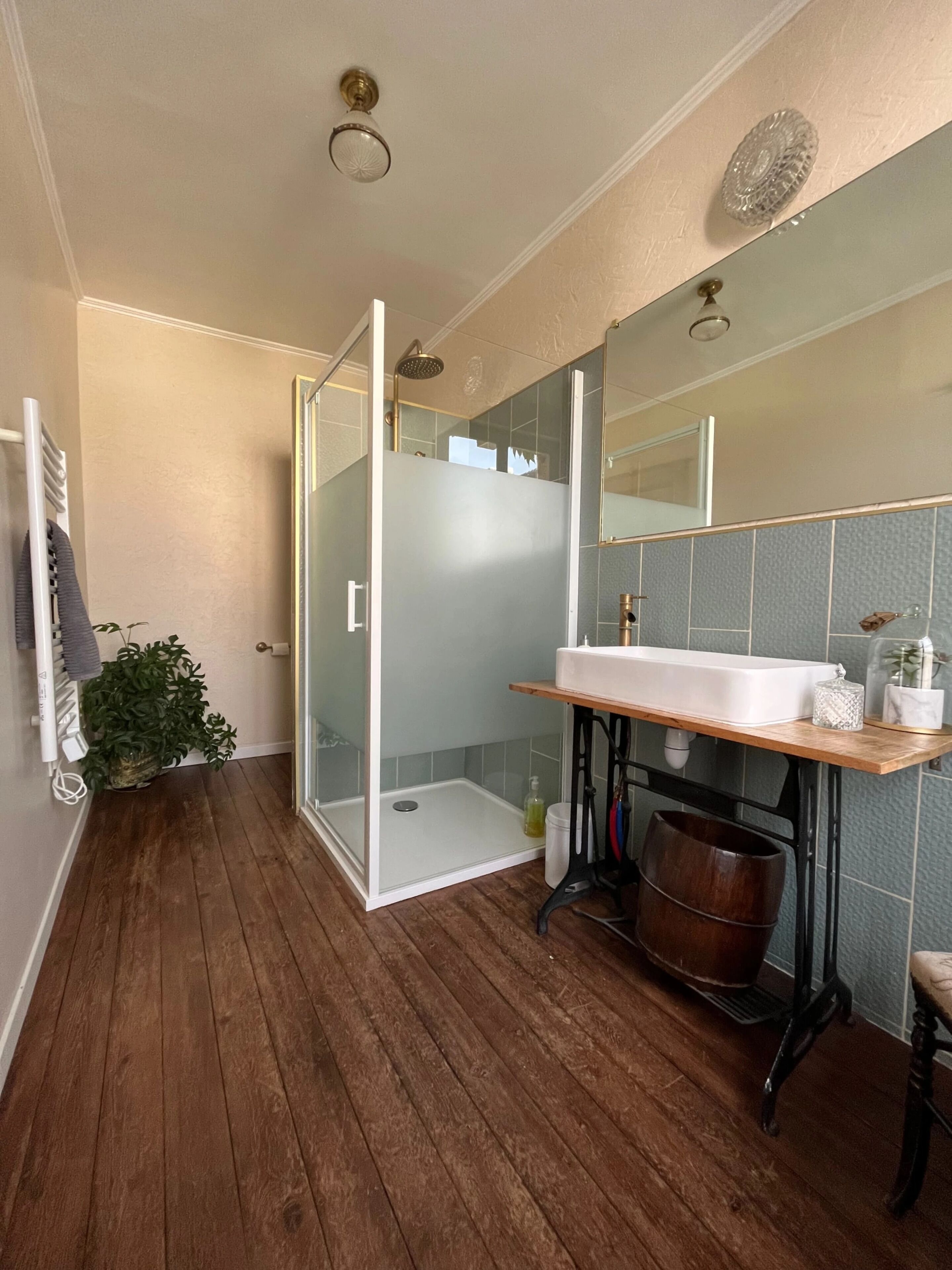Un baño moderno con cabina de ducha de vidrio, tocador de madera y un espejo grande.