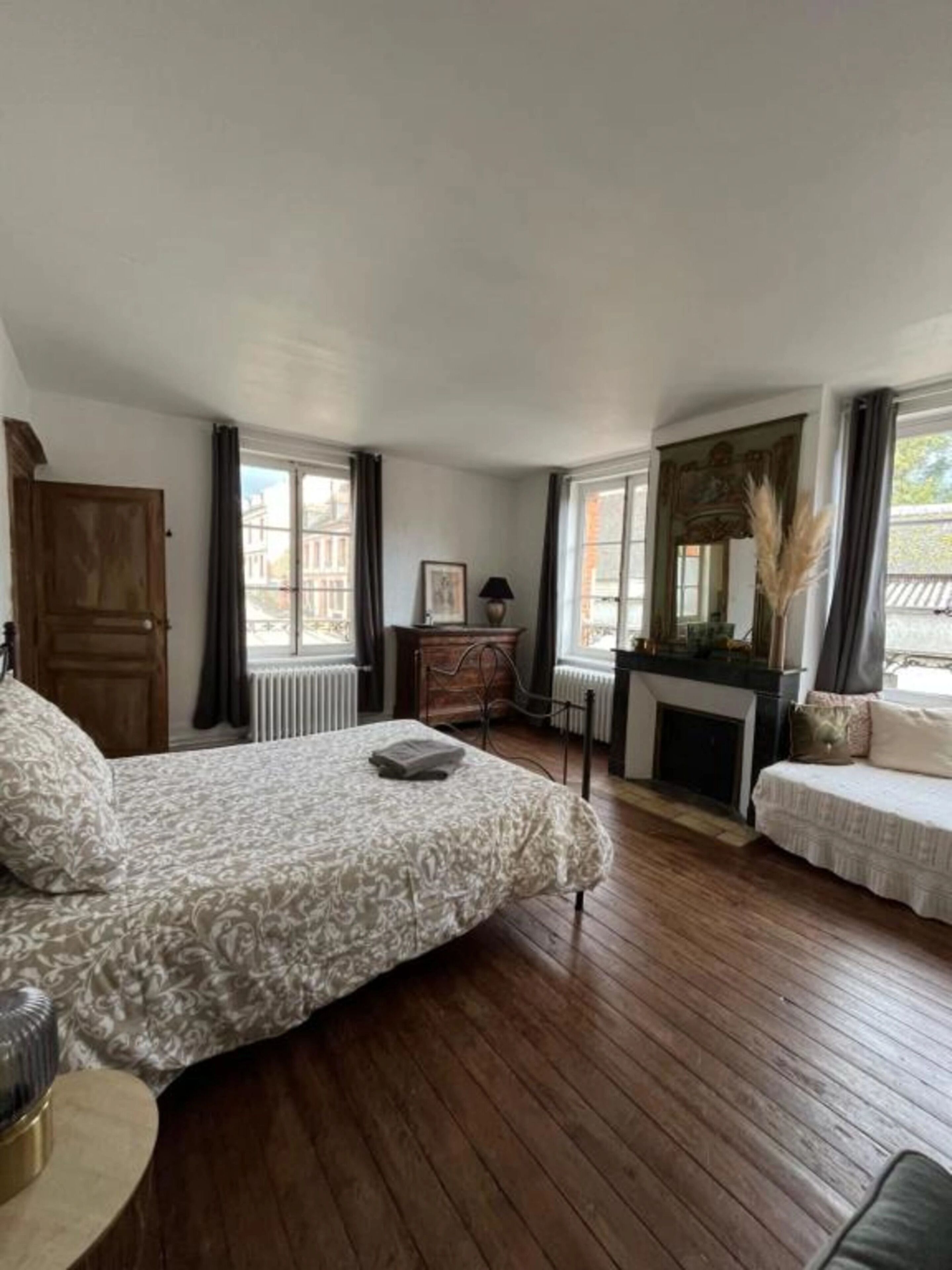 Une chambre avec un grand lit, une cheminée, un canapé et un bureau.