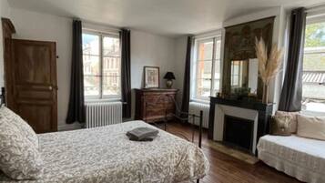 Une chambre avec un grand lit, une cheminée, un canapé et un bureau.