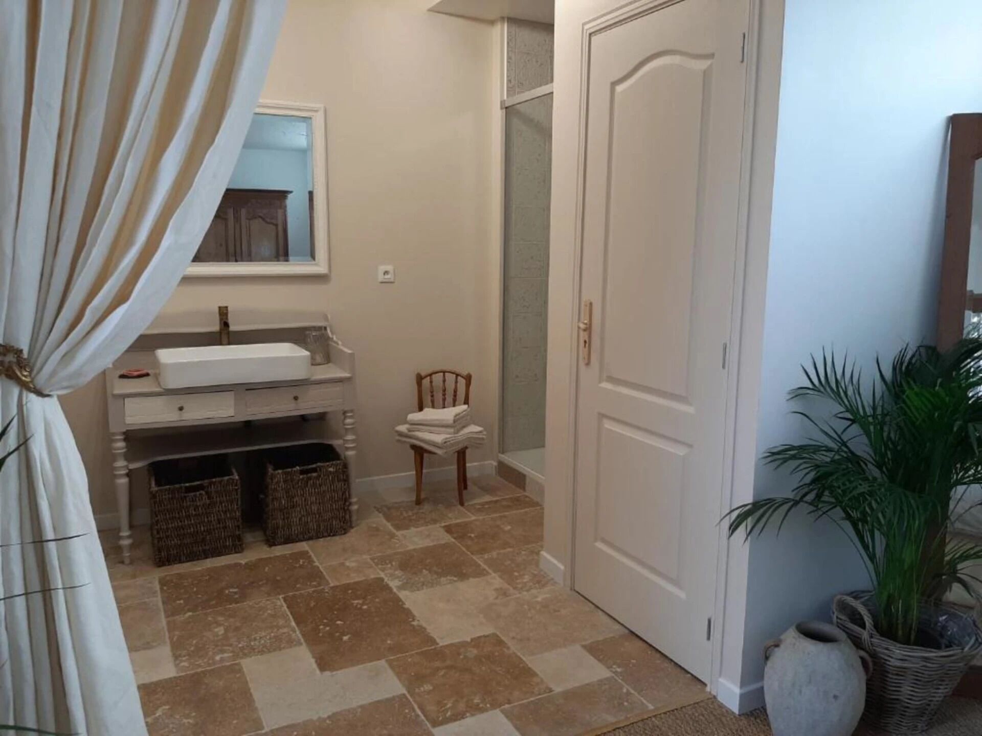 Une salle de bain avec un lavabo, un miroir et deux paniers en osier posés sur le sol.