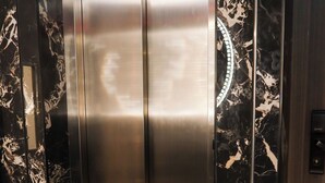 An elevator with a metallic finish and marble-patterned walls. - Unit 3.105/6 (Singapore)