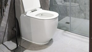 A modern bathroom with a white toilet, a glass shower enclosure, and a marble-tiled floor. - Unit 3.105/6 (Singapore)