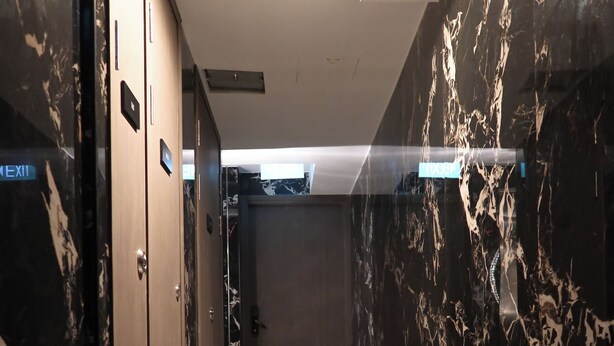 A hallway with marble flooring and walls, featuring a door with a sign that reads "EXIT". - Unit 3.105/6 (Singapore)