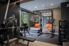 A gym with weightlifting equipment, a bench, and exercise balls.
