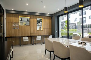 A modern dining area with a long table and chairs, wooden paneling, and a view of the outside.