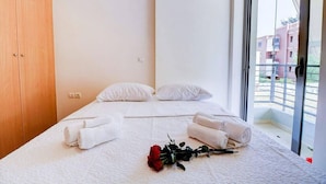A bedroom with two beds, a wooden wardrobe, and a balcony with a view of buildings. - Brand new flat in the amazing area of       Alimos (Alimos)