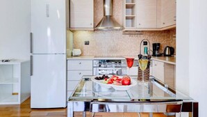 A modern kitchen with a glass dining table, white cabinets, and a stainless steel range hood. - Brand new flat in the amazing area of       Alimos (Alimos)