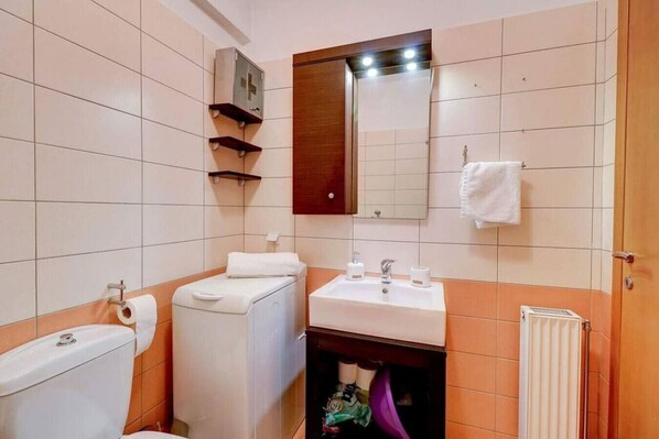 A bathroom with a toilet, bidet, sink, mirror, towel rack, and storage shelves. - Brand new flat in the amazing area of Alimos (Alimos)
