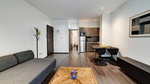 A modern living room with a sofa, a coffee table, and a dining area with a table and chairs. - Classy and stylish apartment next to Hilton (Athina)