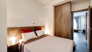 A modern hotel room with a large bed, a wooden headboard, and a wardrobe. - Classy and stylish apartment next to Hilton (Athina)