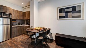 A modern kitchen with dark wood cabinets, a stainless steel refrigerator, and a dining area with a wooden table and chairs. - Classy and stylish apartment next to Hilton (Athina)