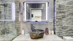 A modern bathroom with a stone sink, a large mirror, and a glass shower enclosure. - Nancy   s studio at metro Petralona (Athina)