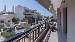 A balcony with a view of a street, buildings, and parked cars. - Blue Pearl at Glufada sea side (Glifada)