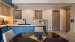 A modern kitchen with a central island, a dining table with chairs, and a coffee machine. - Blue Pearl at Glufada sea side (Glifada)