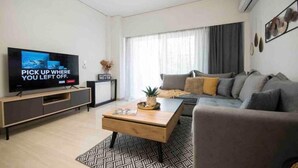 Ein modernes Wohnzimmer mit Flachbildfernseher, einer Couch, einem Couchtisch und einer Heizung.
