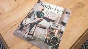 Ein Holztisch mit einem Tischmagazin mit dem Titel „Sotheby's Miro Rediscovered“ und einem kleinen Topfpflanzen.