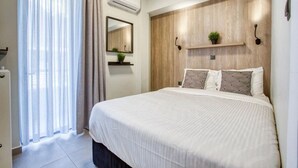Um quarto moderno com uma cama grande, cabeceira de madeira, uma pequena planta e um espelho sobre a cama.