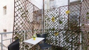 A small outdoor seating area with a table and two chairs, surrounded by a metal fence with climbing plants. - A little gem in the heart of Athens (Athina)