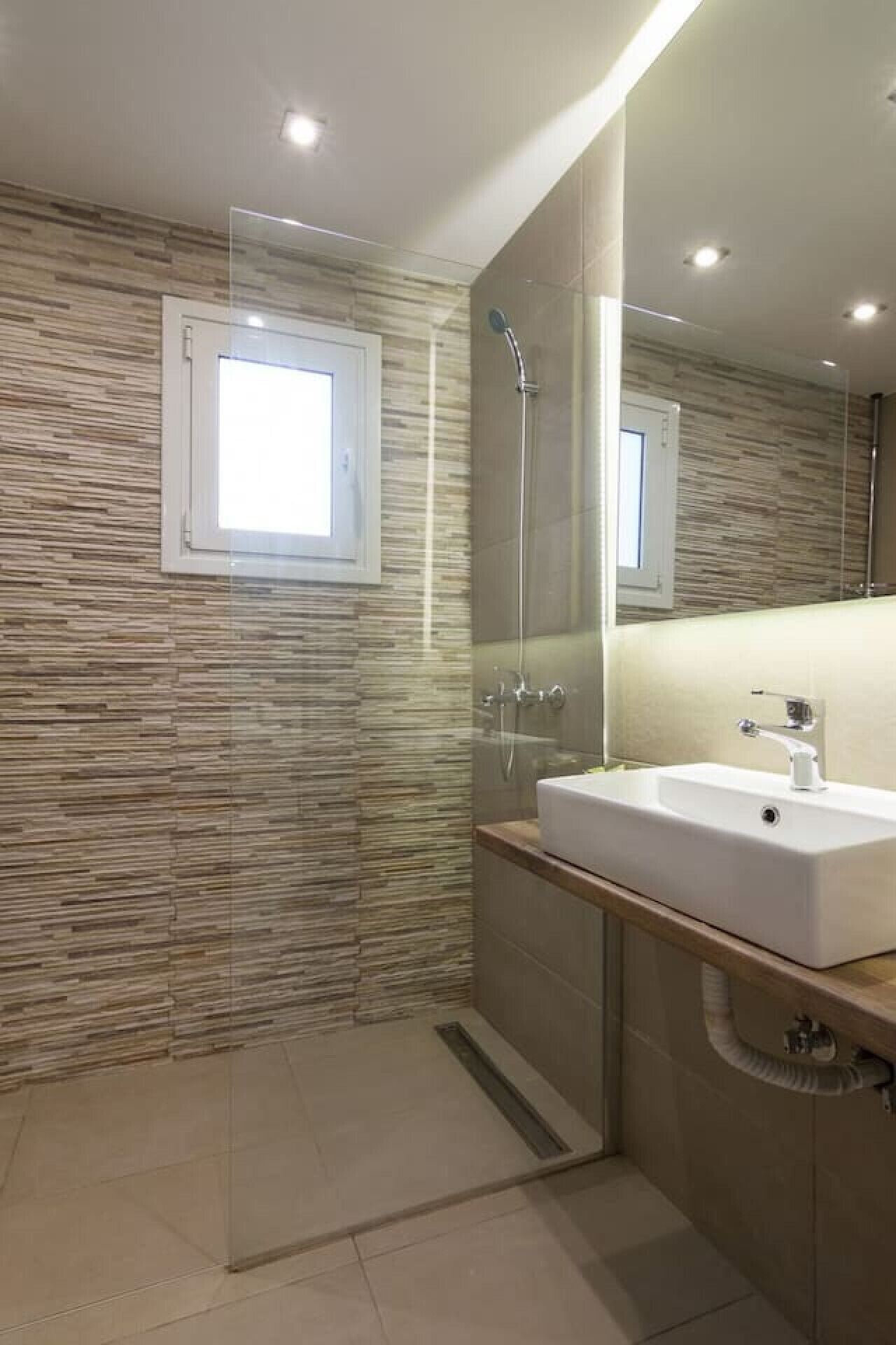 A modern bathroom with a glass shower enclosure, a white sink, and a large mirror.