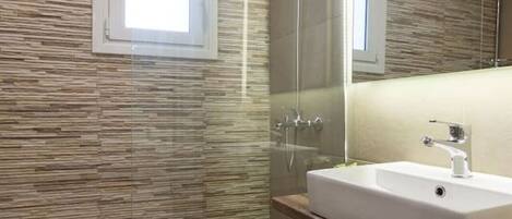 A modern bathroom with a glass shower enclosure, a white sink, and a large mirror.