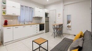 A modern kitchen with white cabinets, a wooden countertop, and a small dining area with a table and chairs. - A little gem in the heart of Athens (Athina)