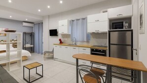 A modern kitchen with white cabinets, stainless steel appliances, and a wooden dining table. - A little gem in the heart of Athens (Athina)