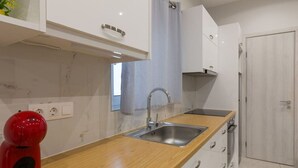 A modern kitchen with a wooden countertop, stainless steel sink, and white cabinets. - A little gem in the heart of Athens (Athina)