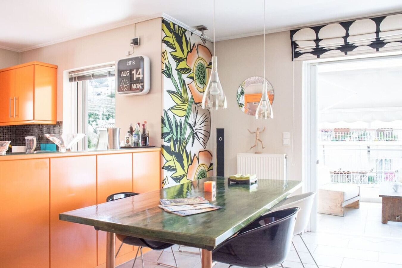 A modern kitchen with a green marble countertop, a black chair, and a decorative plant.