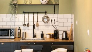 A modern kitchen with a wooden table, black cabinets, and a white tiled backsplash.