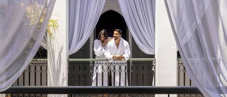 A balcony with white drapes and a wrought iron railing.