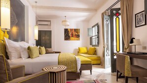 Ein Hotelzimmer mit Bett, Schreibtisch, Sessel, Sofa und einem farbenfrohen Teppich.