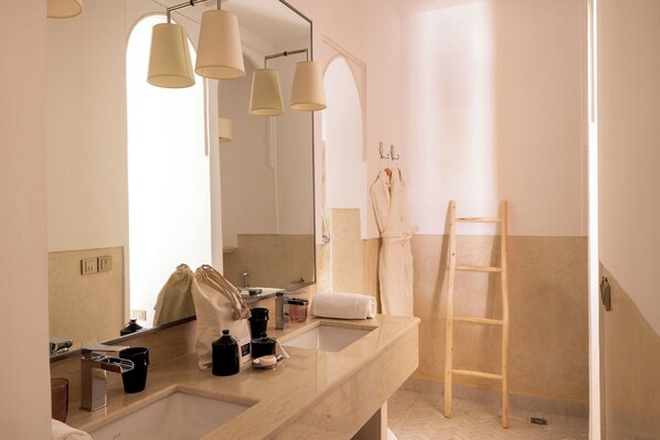 Une salle de bain avec un grand miroir, un lavabo, une serviette, une échelle en bois et un sac.