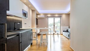 A modern kitchen with a central island, a dining area with stools, and a balcony with a view.