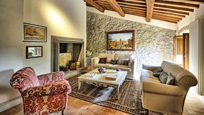 A living room with a stone wall, wooden beams, a fireplace, and two sofas.